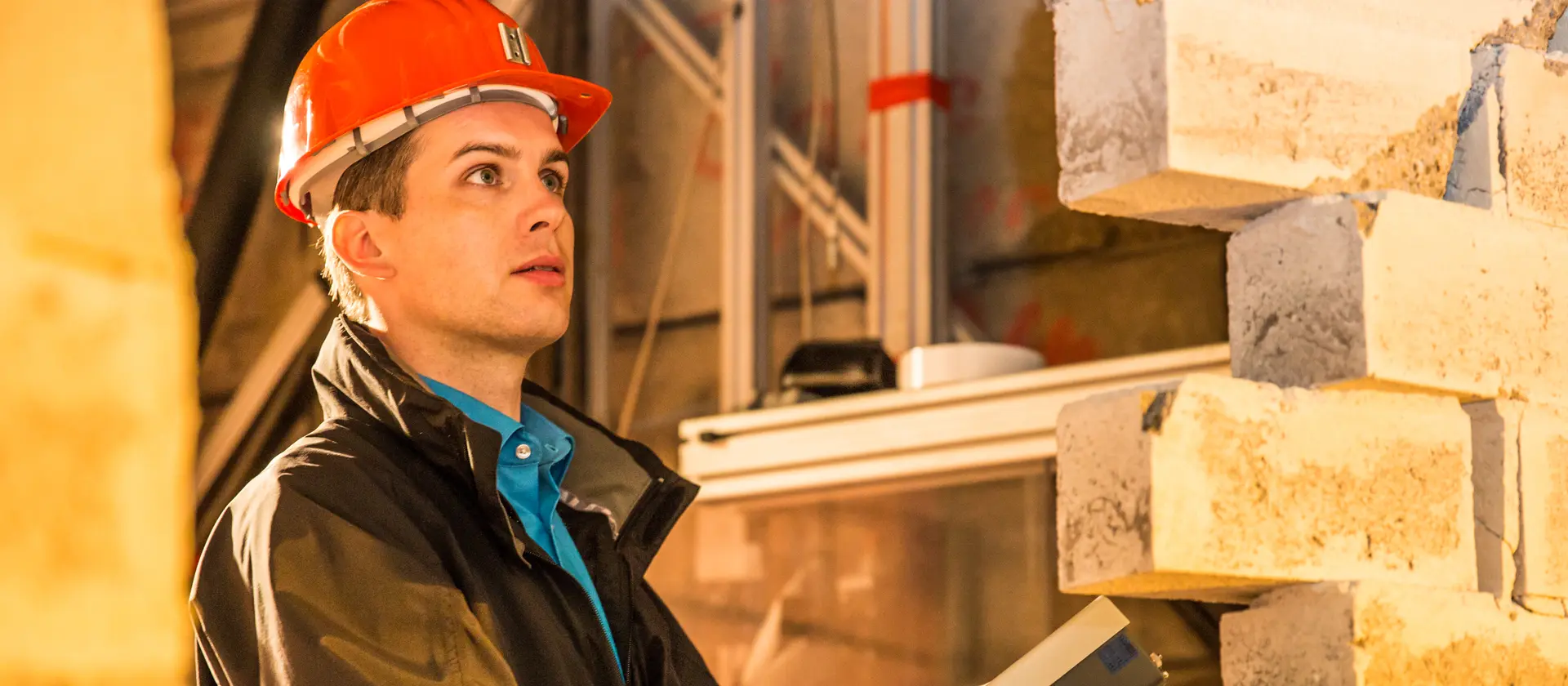 Ein Mann mit orangenem Baustellenhelm überprüft eine gemauerte Wand