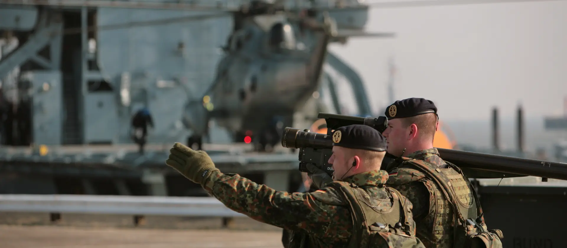 Zwei Soldaten mit Kameraausrüstung filmen ein Schiff.