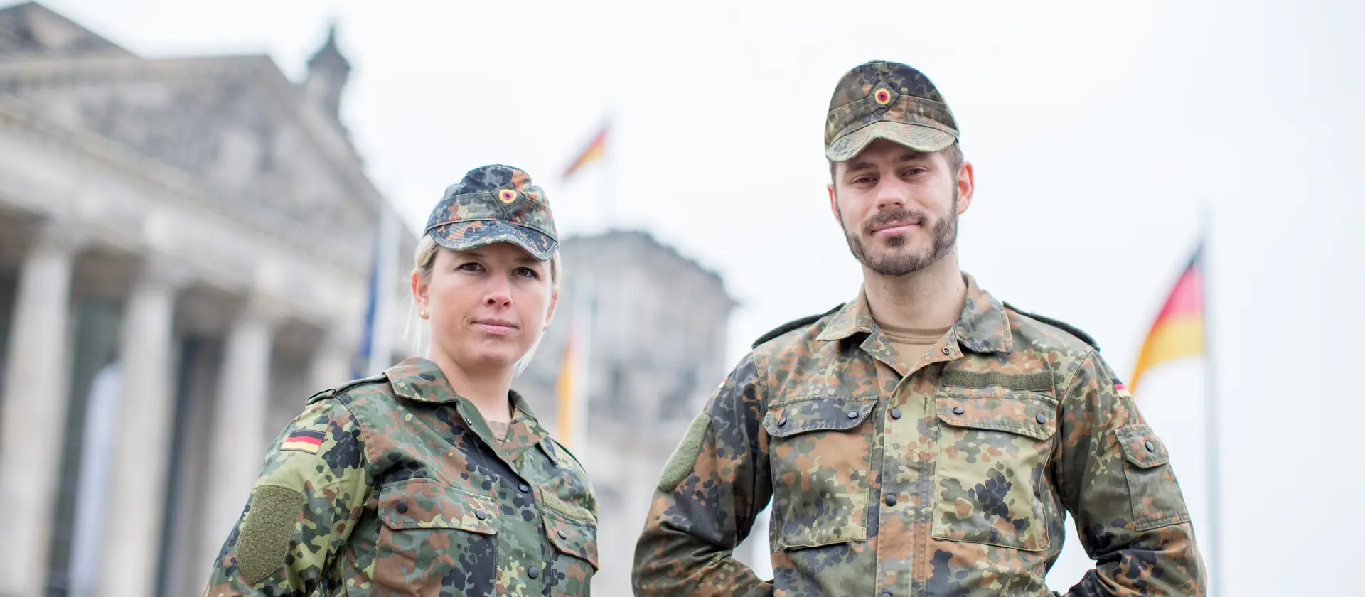Eine Soldatin und ein Soldat stehen auf der Wiese vor dem Reichstag in Berlin