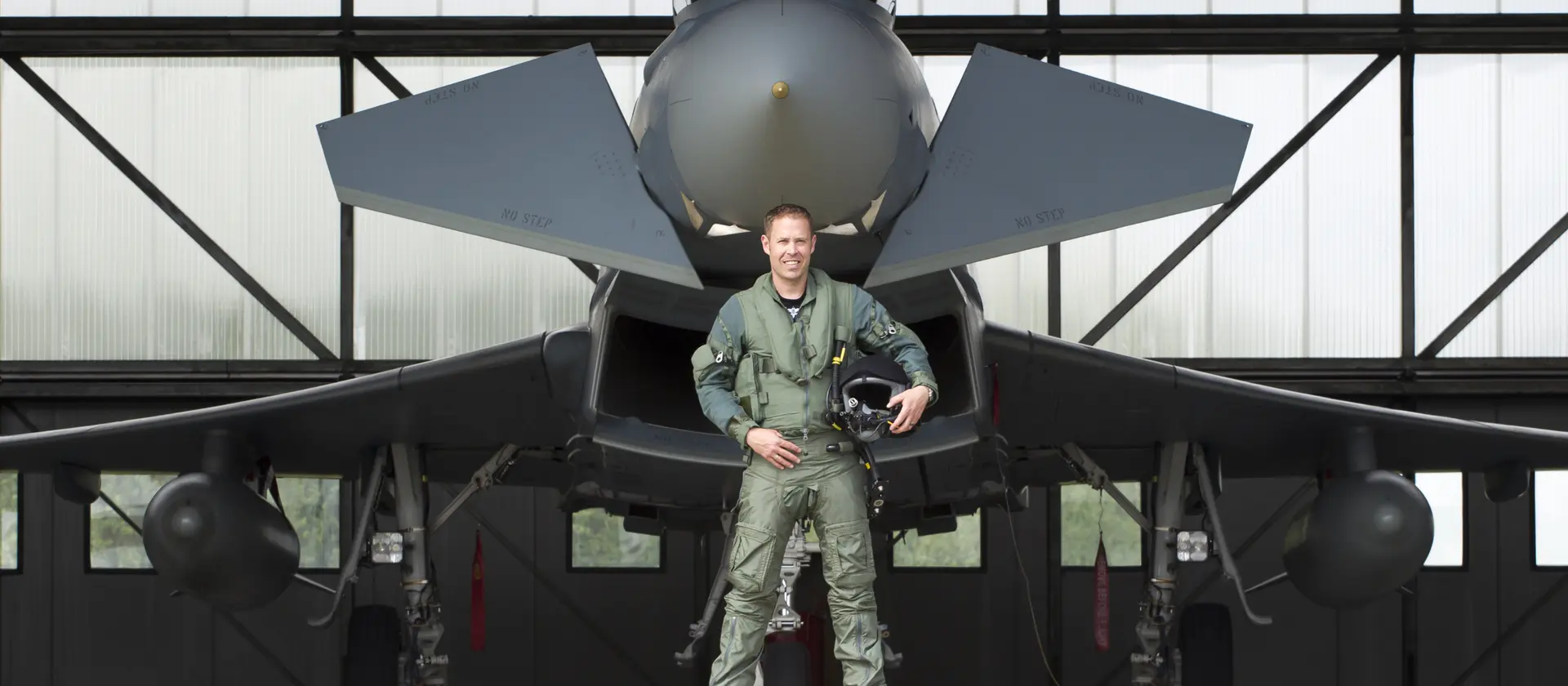 Ein Soldat der Bundeswehr steht vor einem Kampfjet, welcher in einem Hanger steht.