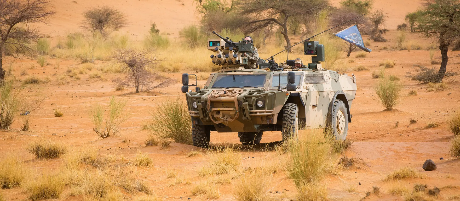 Ein gepanzertes Bundeswehrfahrzeug mit Antennen und Maschinengewehr steht im Gelände