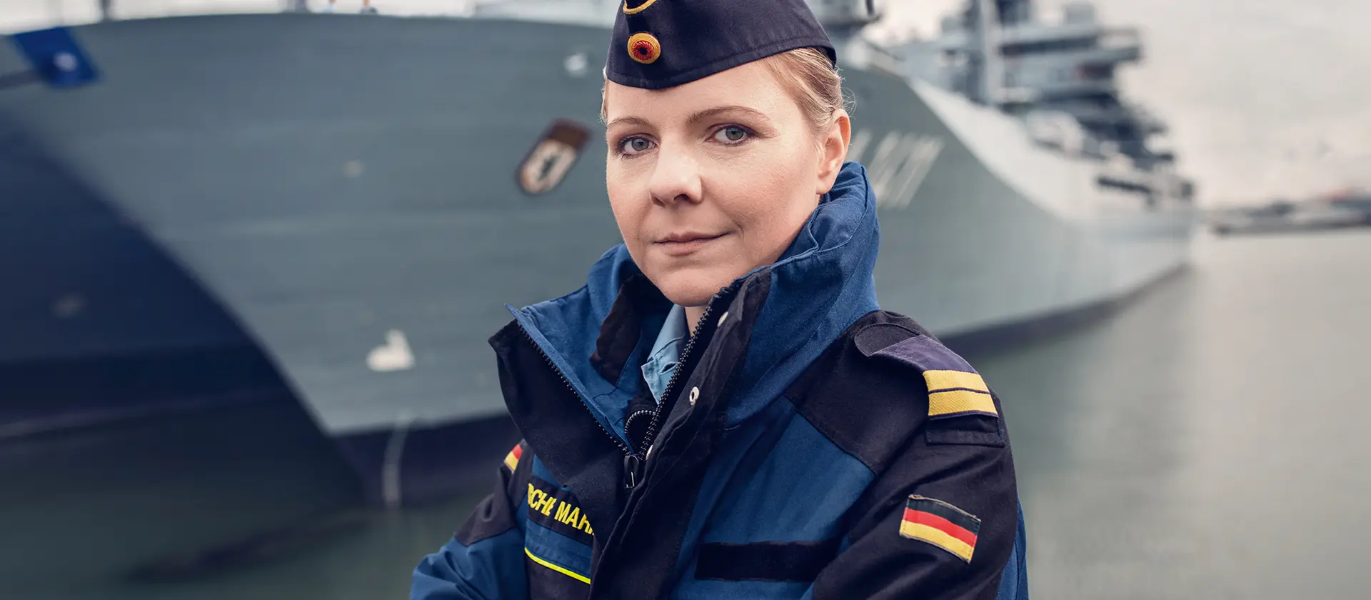 Offizierin der Marine steht vor einem Schiff