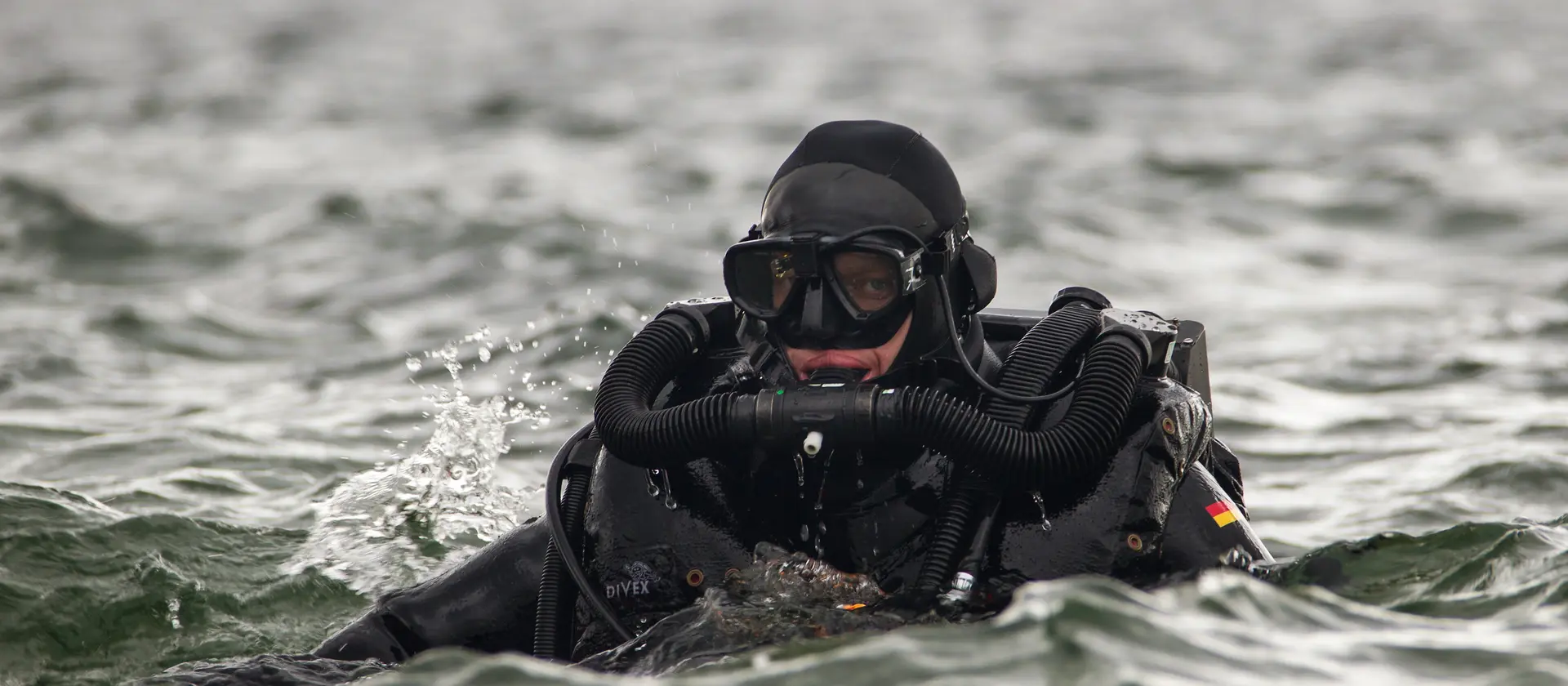 Minentaucher_in taucht aus dem Wasser auf
