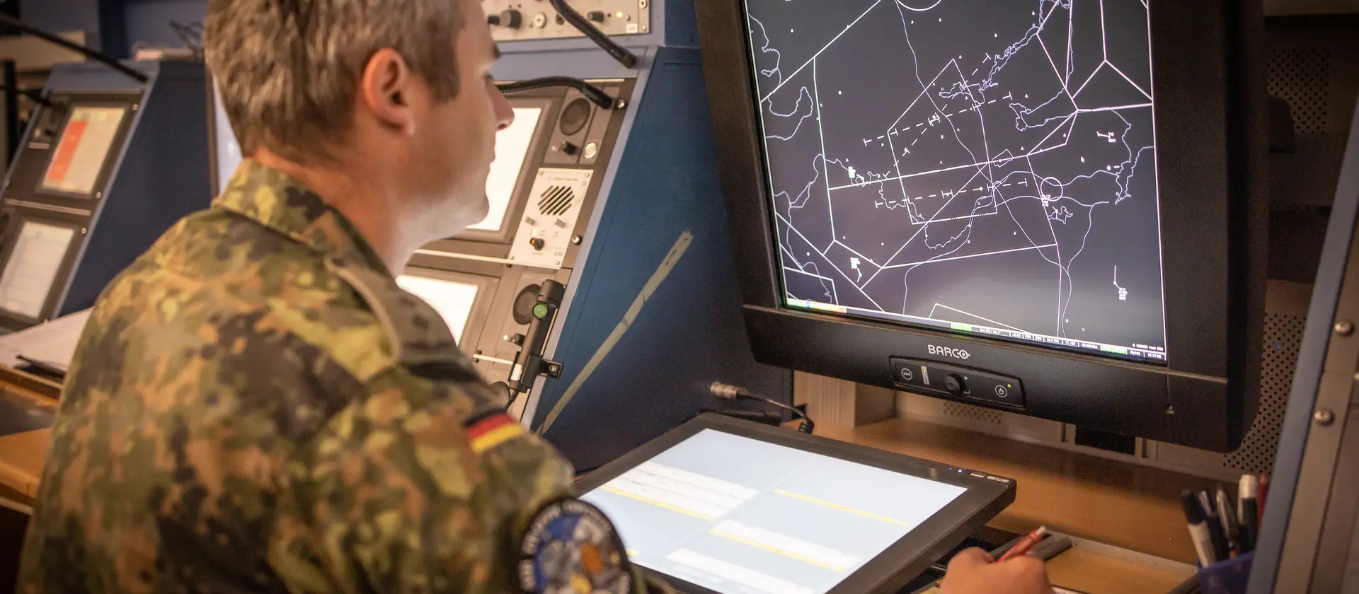 Ein Soldat schaut auf einen Monitor, auf dem eine schwarz-weiße Karte zu sehen ist