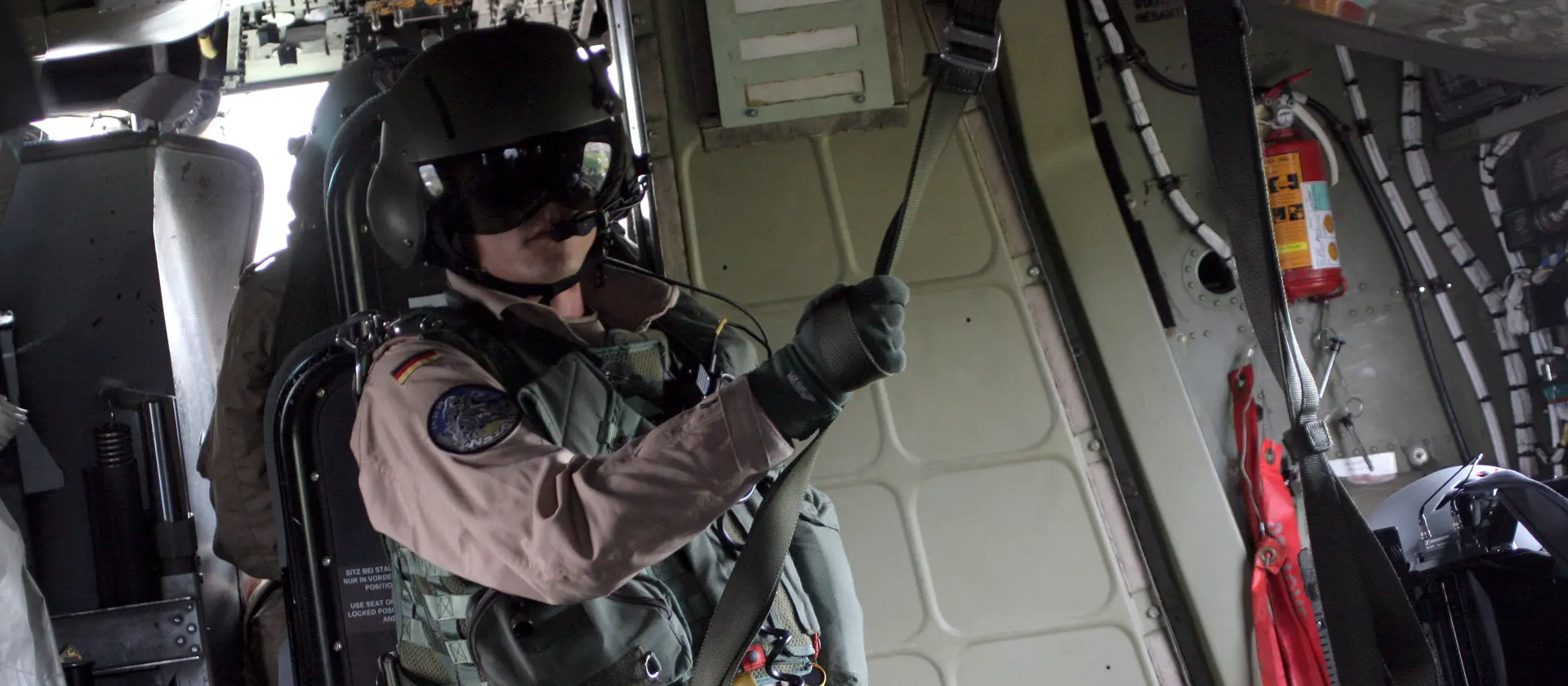 Bordtechniker in Uniform steht gesichert an einer Leine in einem Flugzeug