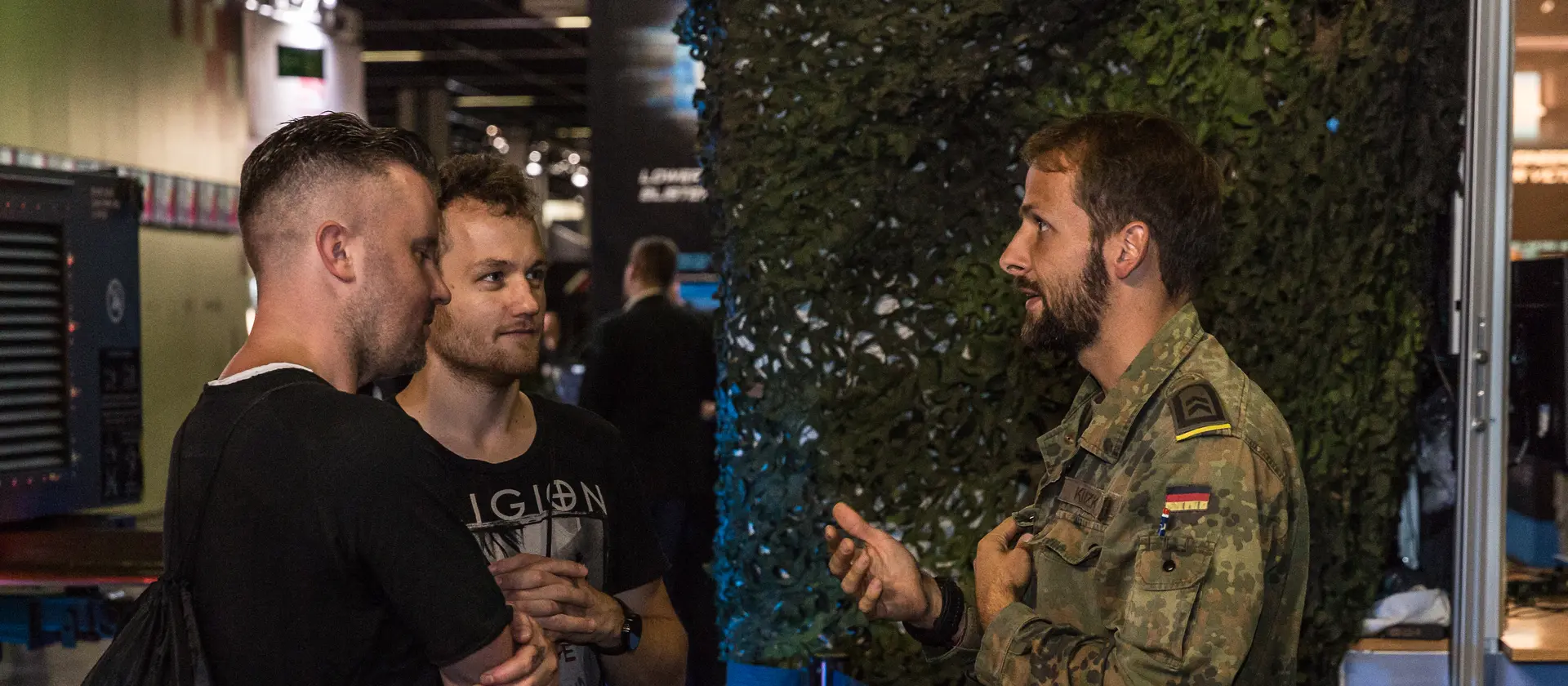 Ein Bundeswehr-Soldat spricht mit zwei Männern in ziviler Kleidung.