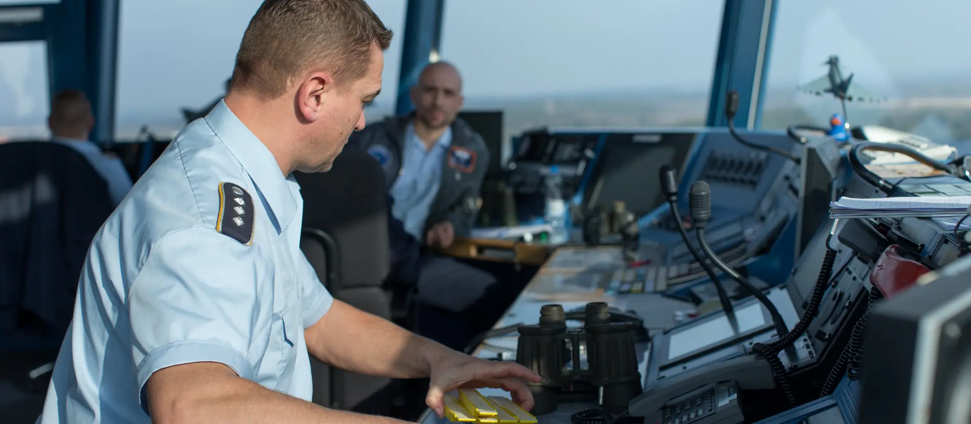 Fluglotse in Uniform sitzt im Tower eines Flugplatzes und koordiniert die Flugbewegungen