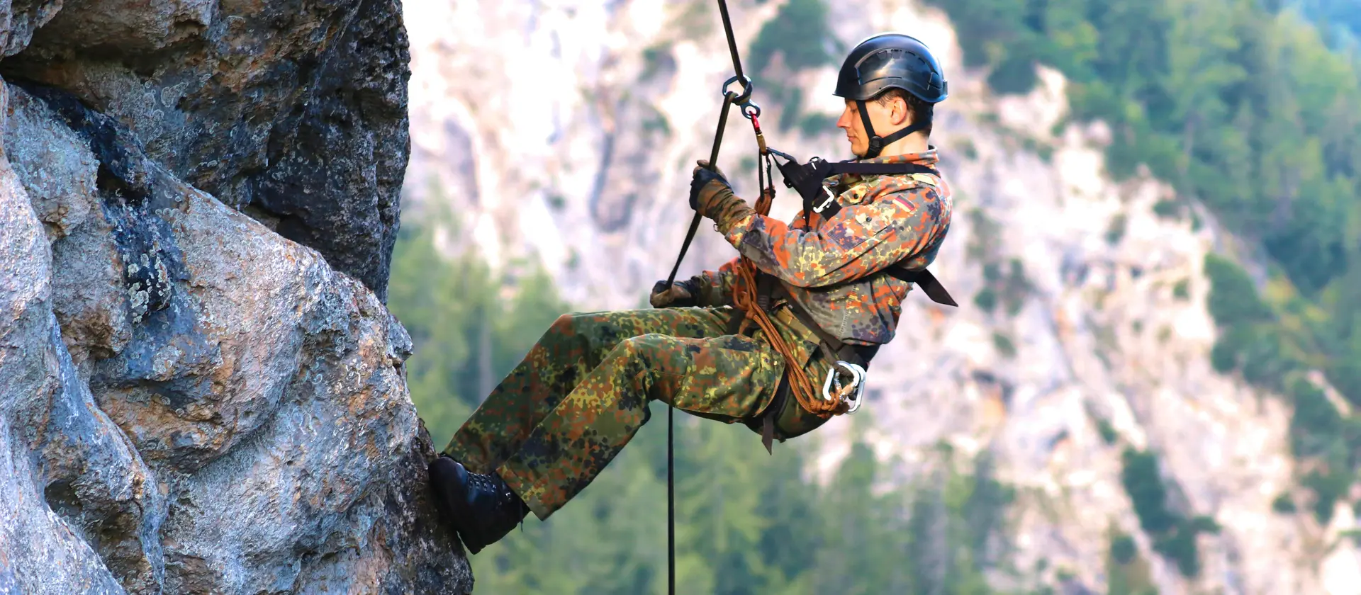 Ein Soldat der Gebirgsjäger seilt sich an einer felswand ab.