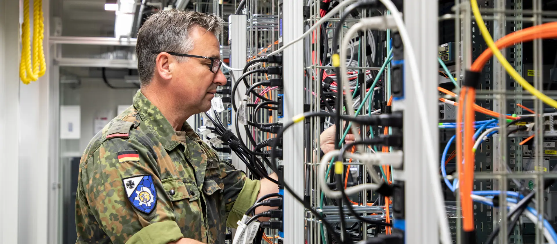 Soldat in einem Serverraum prüft Verkabelungen