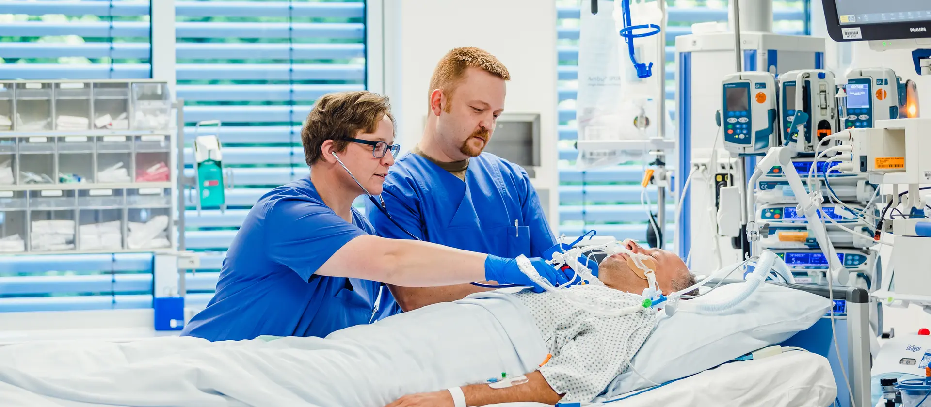 Zwei Pflegefachkräfte arbeiten an einem Patienten, der beatmet wird.