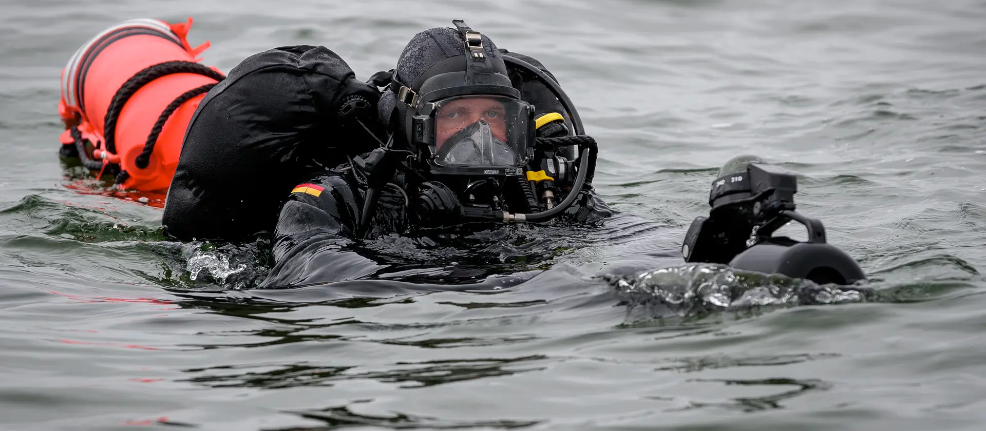 Ein Pioniertaucher mit Boje und weiterer Ausrüstung im Wasser