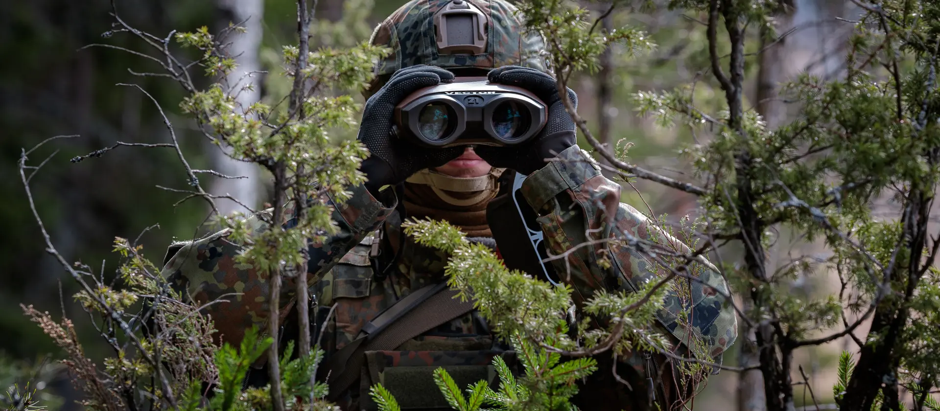 Ein Soldat mit einem Fernglas im Wald