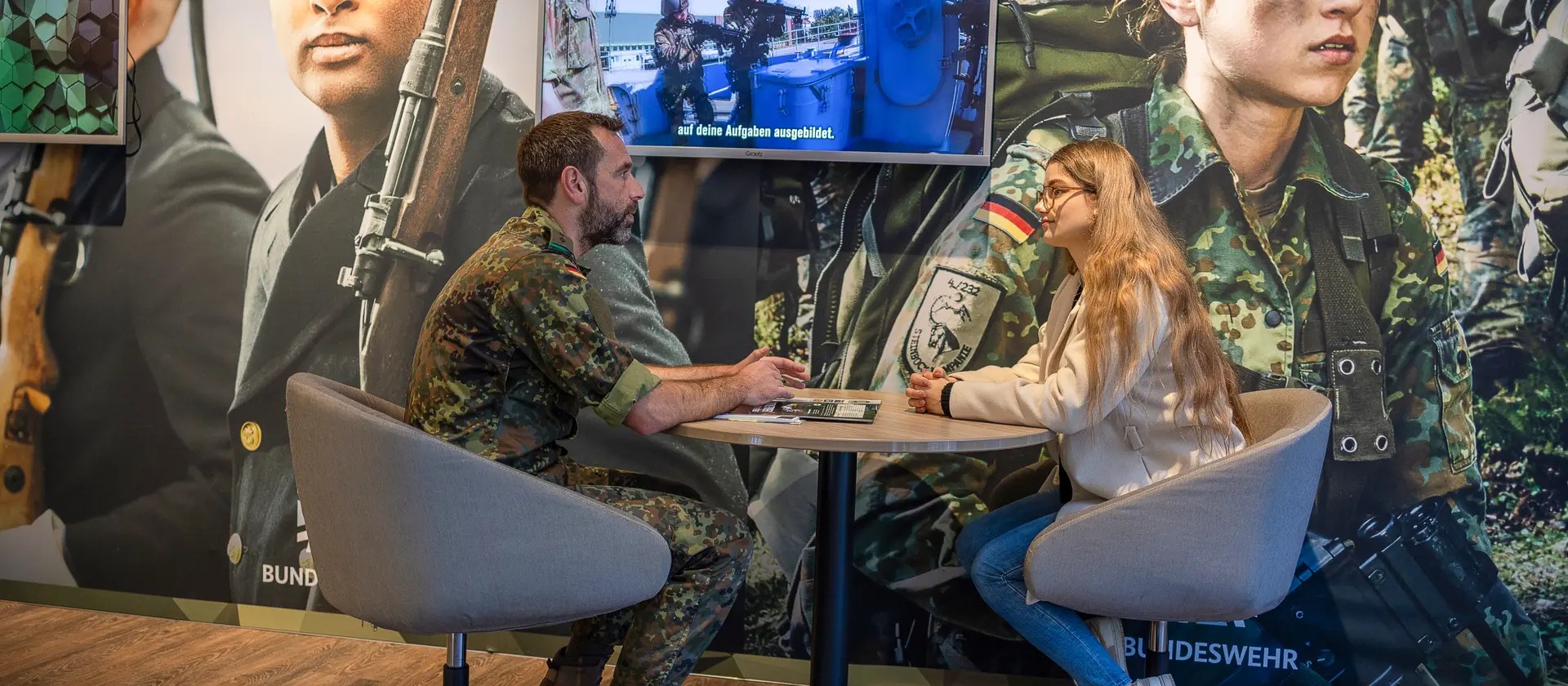 Ein Bundeswehrsoldat sitzt mit einer Frau an einem Besprechungstisch