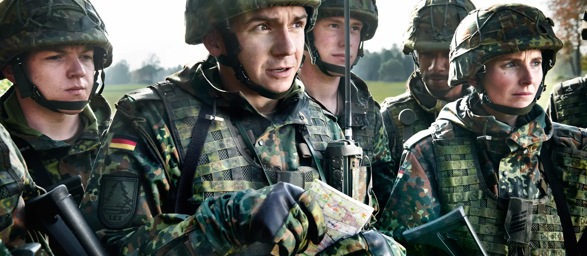 Angehende Offiziere in Flecktarnuniform mit Weste und Helm besprechen die Lage