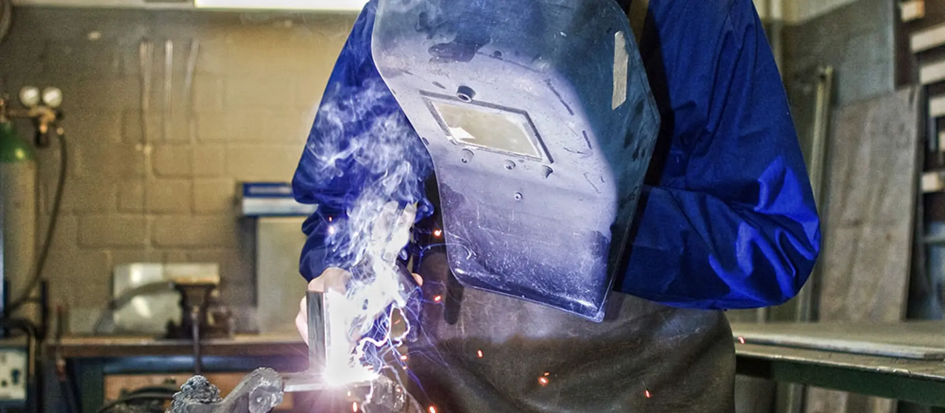 Ein Metallbauer mit Schutzschild schweißt an einem Werkstück