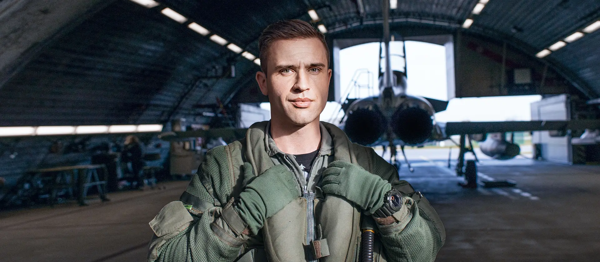 Kampfpilot steht vor einem Hangar mit Kampfflugzeug