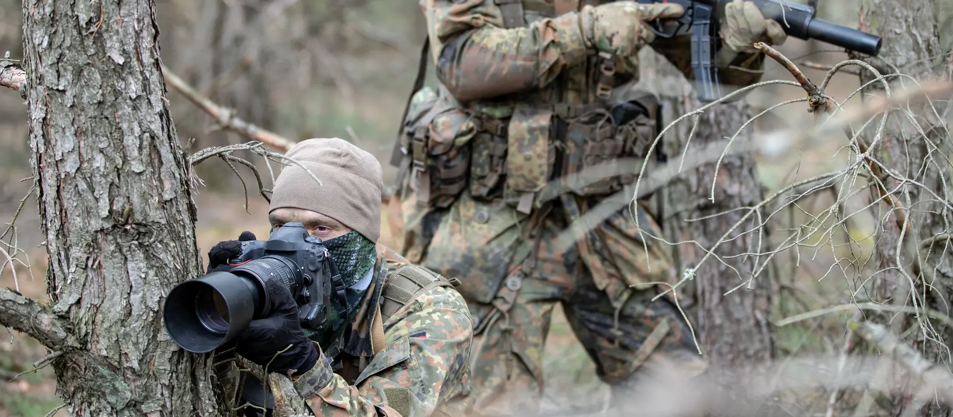 Vermummte Soldaten observieren ein Waldgebiet