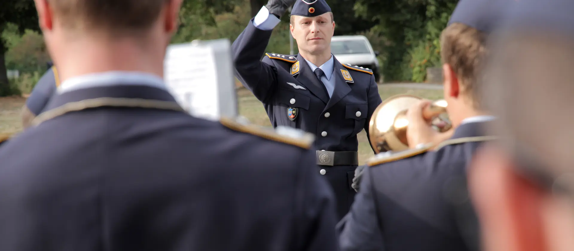 Ein Dirigent in Uniform dirigiert ein Orchester im Freien