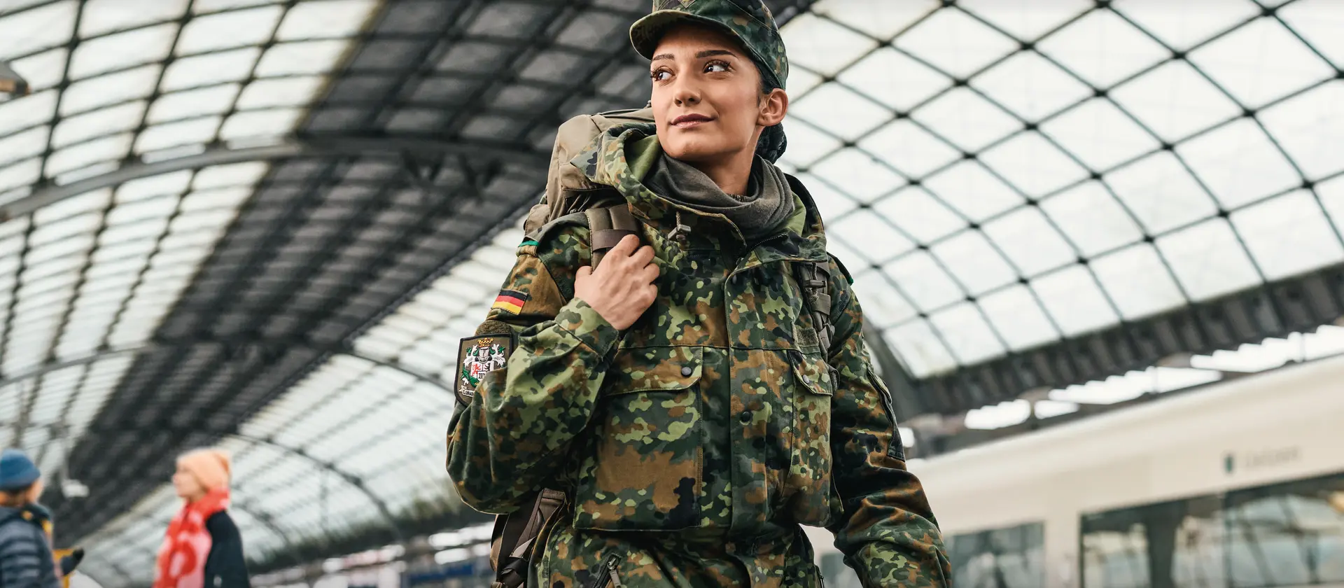 Soldatin in Uniform geht durch einen Bahnhof