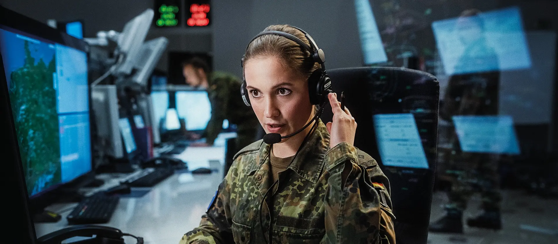 Bundeswehrsoldatin mit Headset arbeitet vor einem Monitor