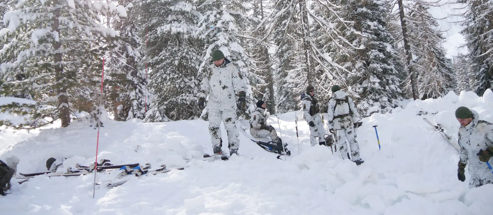 Soldaten der Gebirgsjägertruppe im Schneetarn-Anzug bereiten ihr Lager im Wald vor.