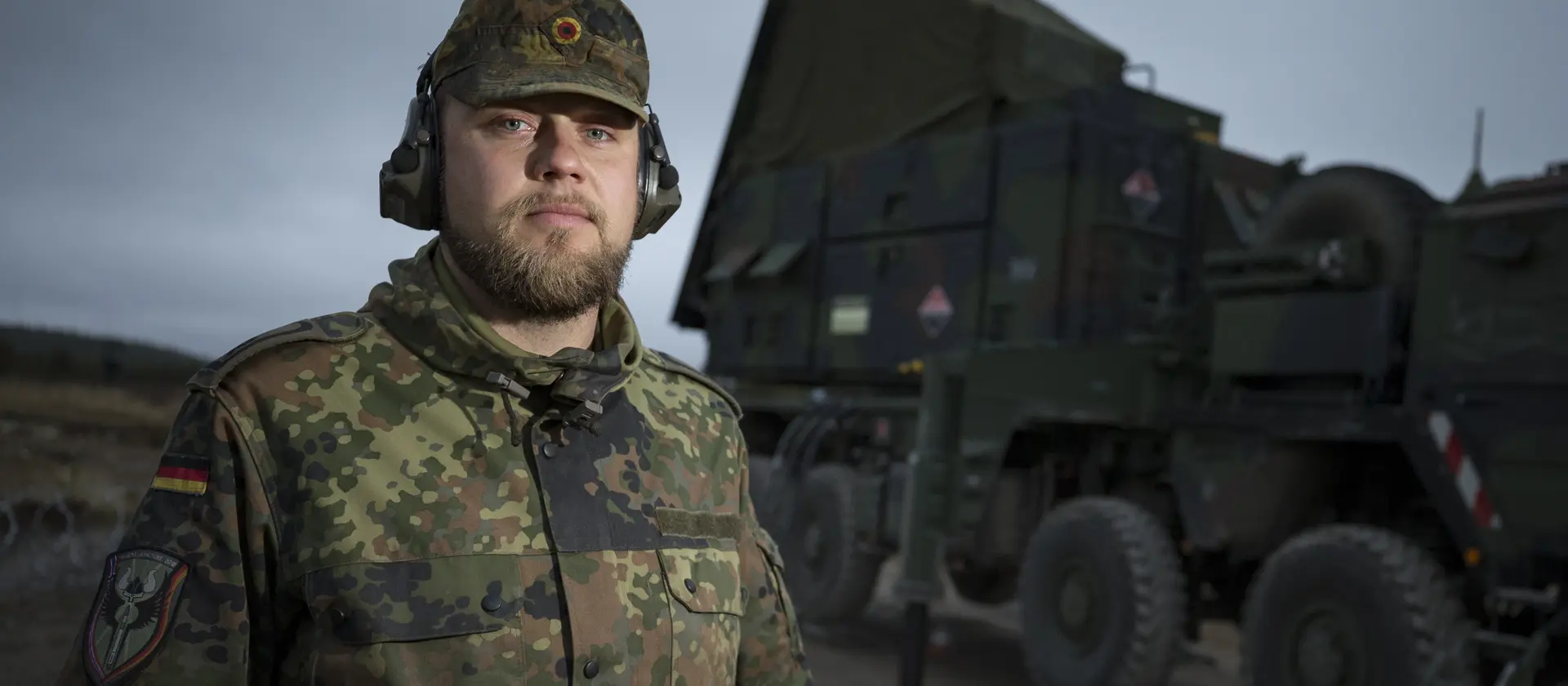 Soldat im Flugabwehrraketendienst steht vor einem großen LKW