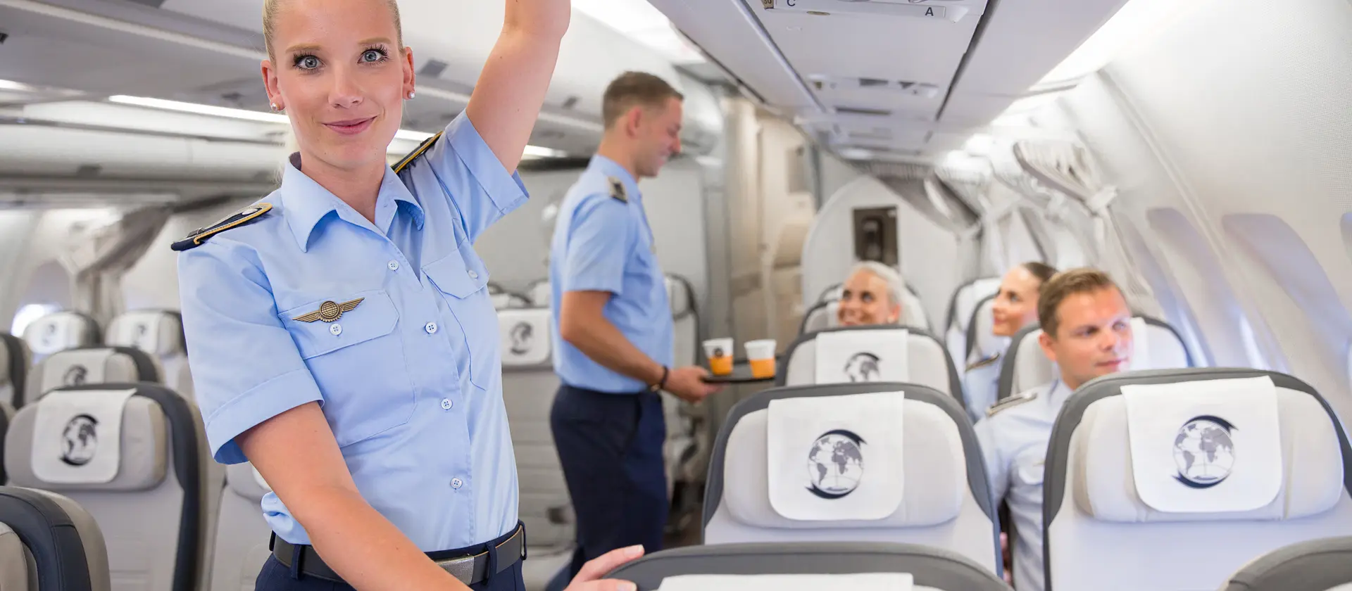 Flugbegleiterin in Unform steht im Gang eines Flugzeugs