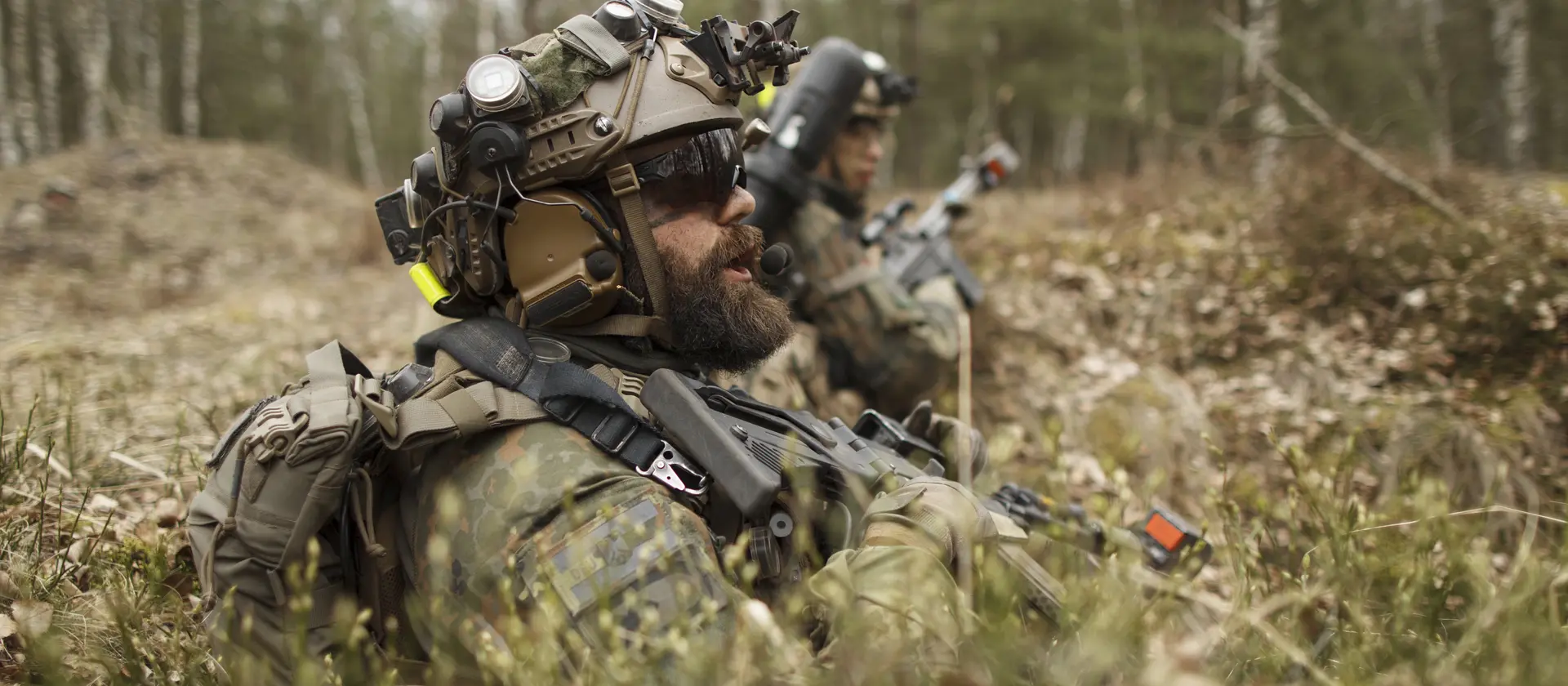 Soldaten liegen im Wald und sichern die Umgebung.
