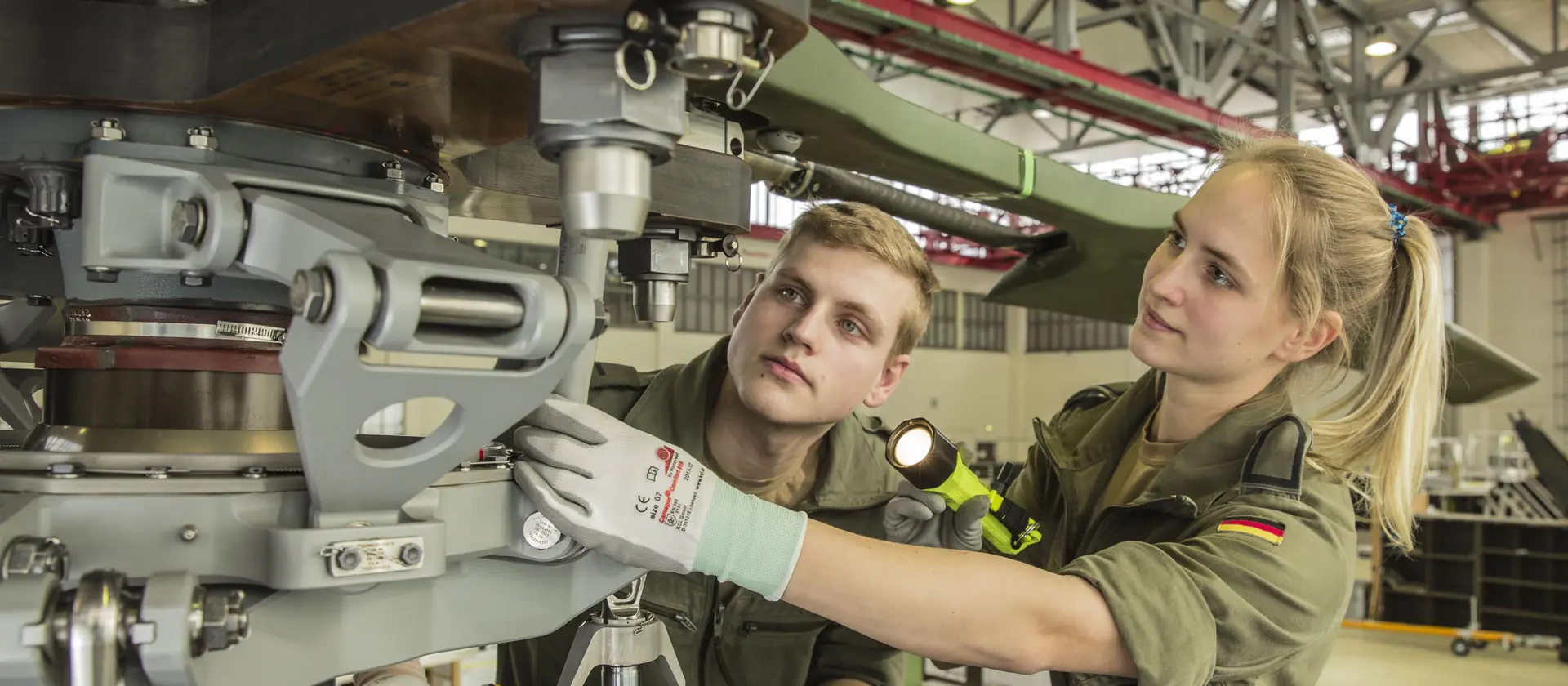 Ein Soldatin und ihr Kamerad prüfen den Rotor eines Hubschraubers.