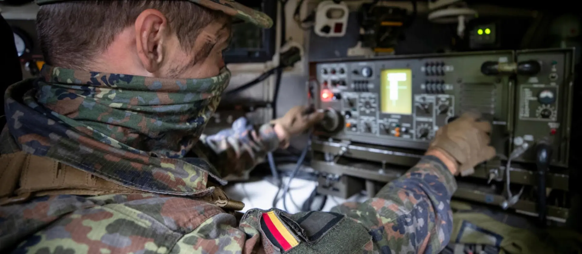 Ein Soldat sitzt in einem gepanzerten Fahrzeug vor einem technischen Gerät