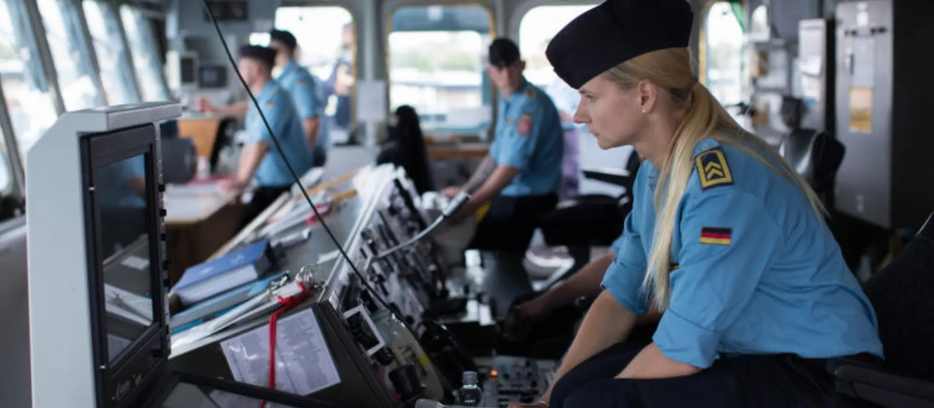 Eine Soldatin beobachtet die Navigationsmonitore auf der Brücke eines Schiffes.