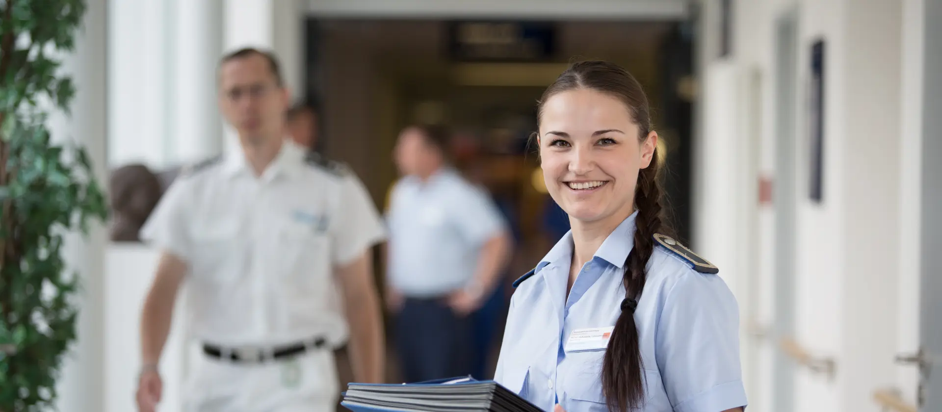Personalsachbearbeiterin in Uniform steht mit Unterlagen in den Händen in einem Flur des Bundeswehrkrankenhauses.