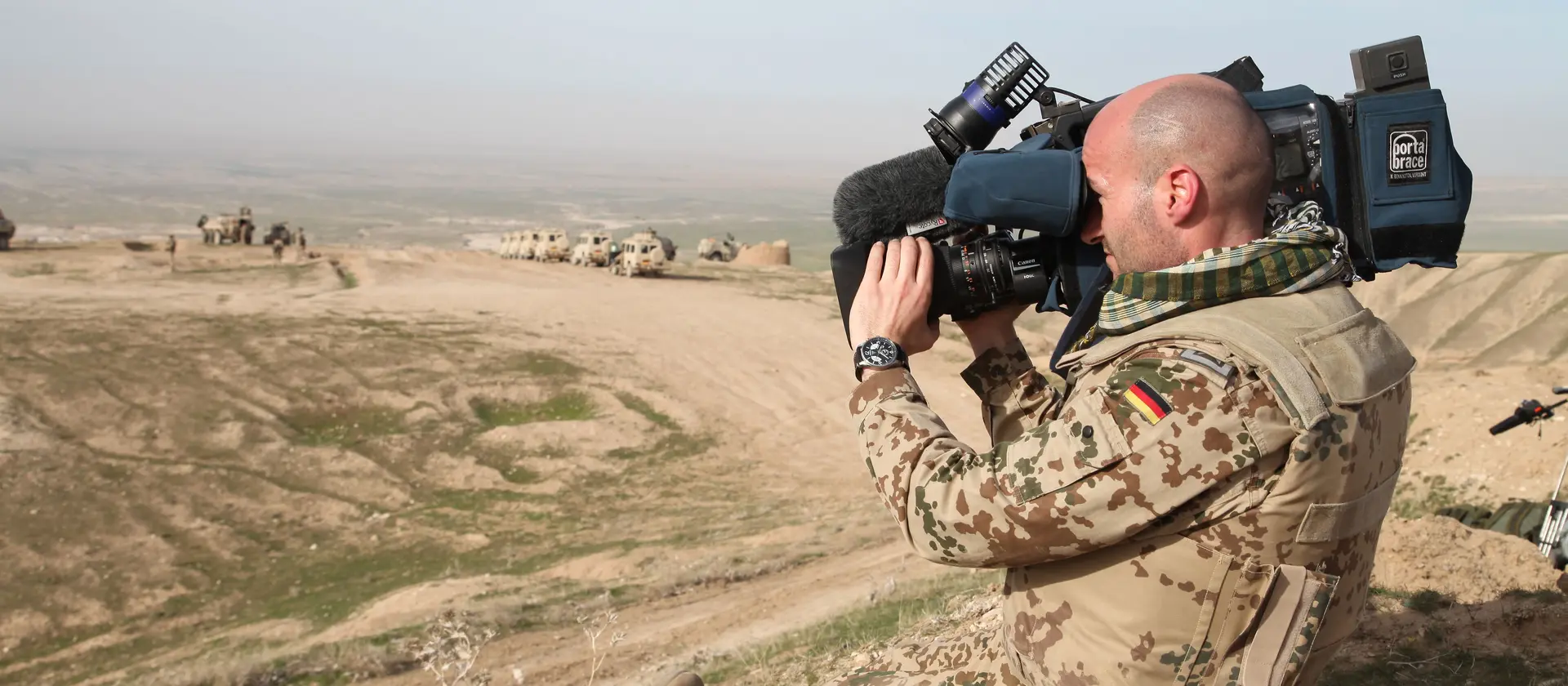 Soldat mit Kamera- und Videoausrüstung filmt in der Wüste.