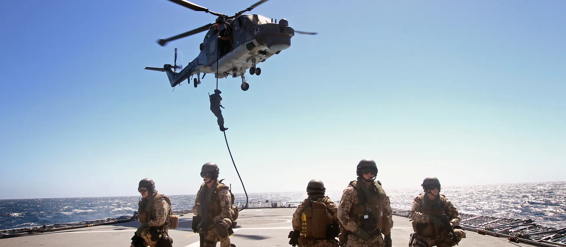 Soldaten der Boardingsicherungstruppe seilen sich aus einem Hubschrauber auf ein Schiff ab.