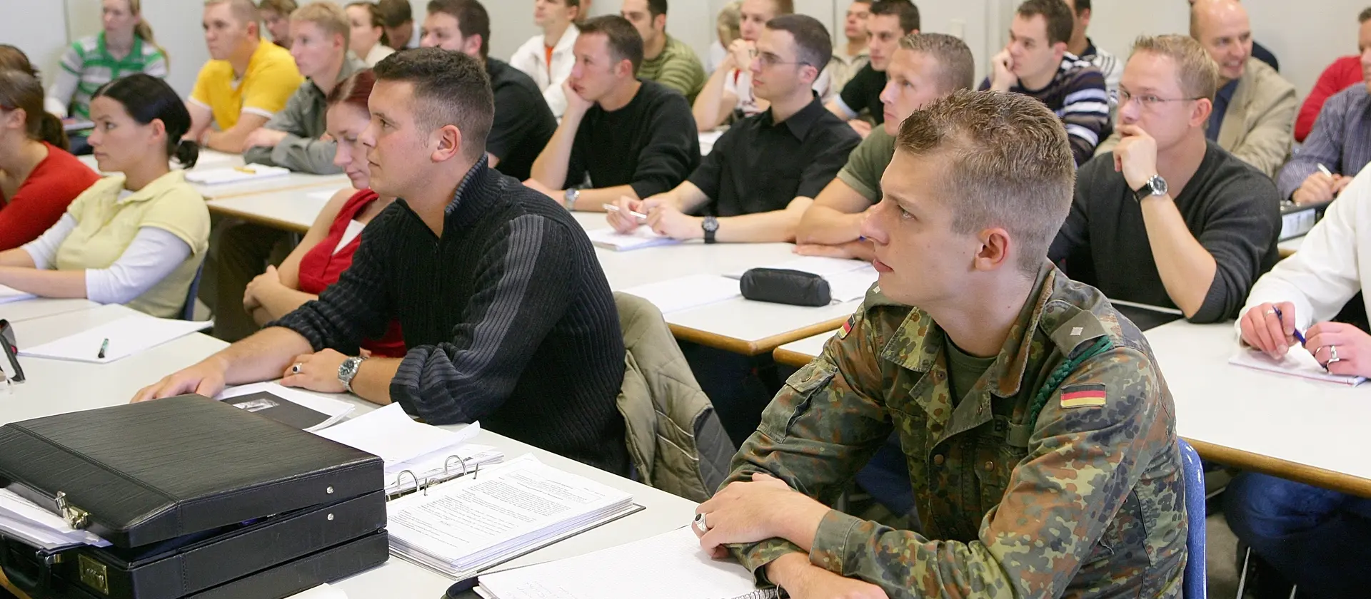 Studenten in Uniform und zivil lauschen einer Vorlesung