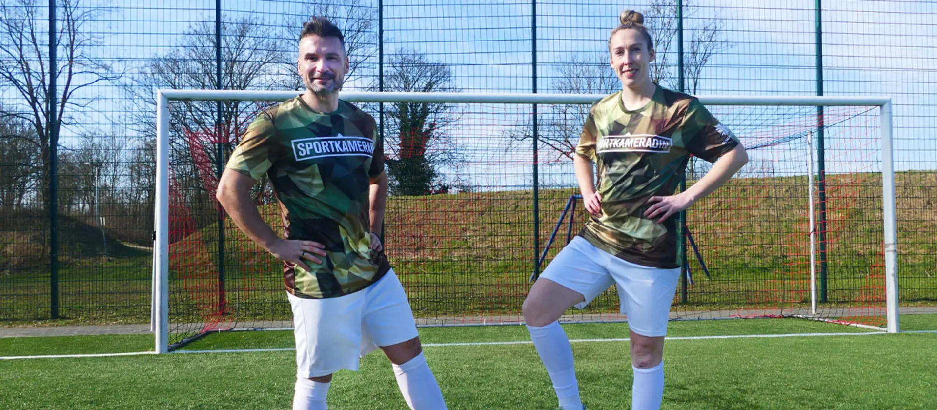 Eine Soldatin und ein Soldat stehen vor einem Fußballtor