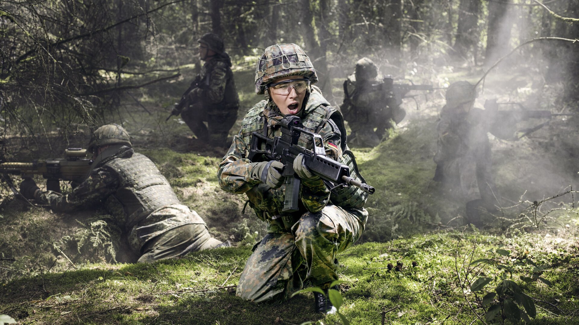 Ein Soldatin mit Gewehr sichert mit Kameraden ein WaldstÃ¼ck