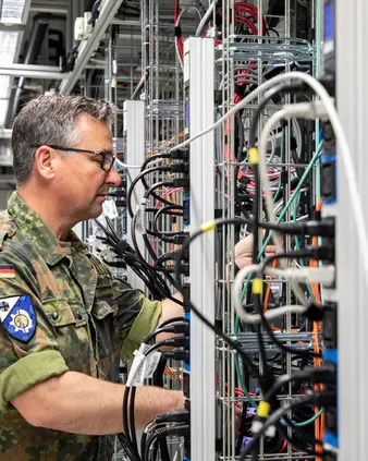 Soldat in einem Serverraum prüft Verkabelungen