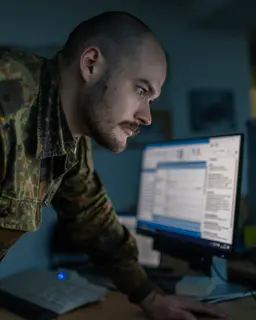Ein Soldat der Bundeswehr steht vor mehreren Monitoren