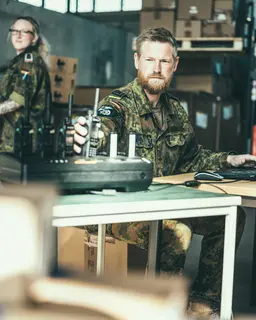 IT-Soldat in Uniform sitzt vor einem Laptop und Funkgerät
