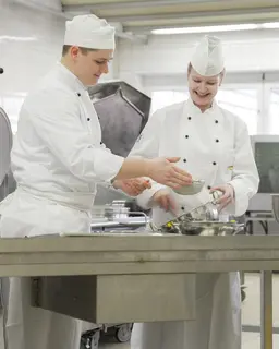 Koch und Köchin bereiten in der Küche Essen zu