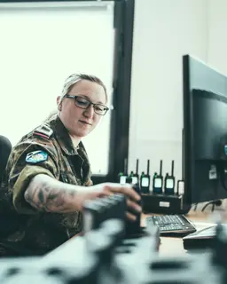 Eine Soldatin sitzt an einem Schreibtisch vor einem Monitor